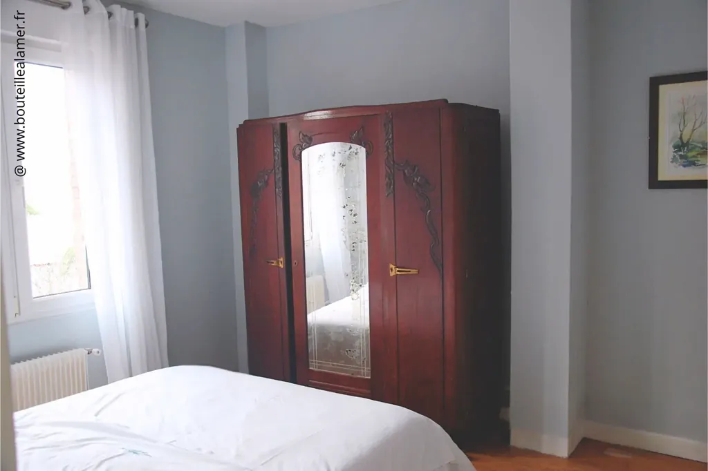 Chambre double lumineuse avec armoire ancienne à miroir, vue jardin côté Club de voile, gîte Bouteille à la Mer sur la Côte d’Opale à Gravelines, location maison de vacances.