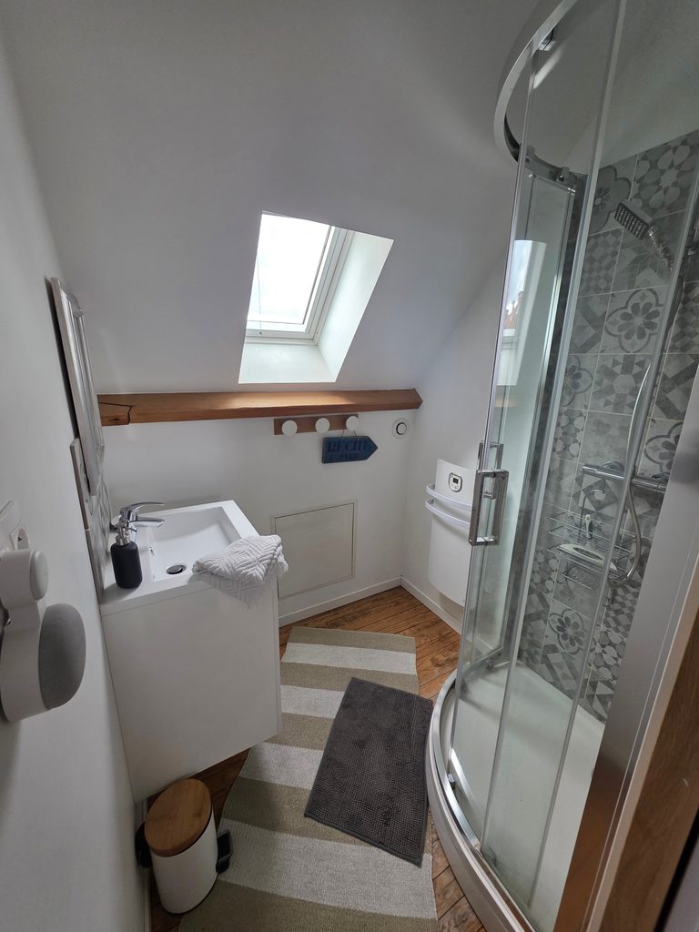 Photo d'une salle de bain chaleureuse du Gîte Bouteille à la Mer avec décoration marine authentique (voilier, bouée) et un grand lit confortable. Parfait pour une location vacances Côte d'Opale près de Gravelines.