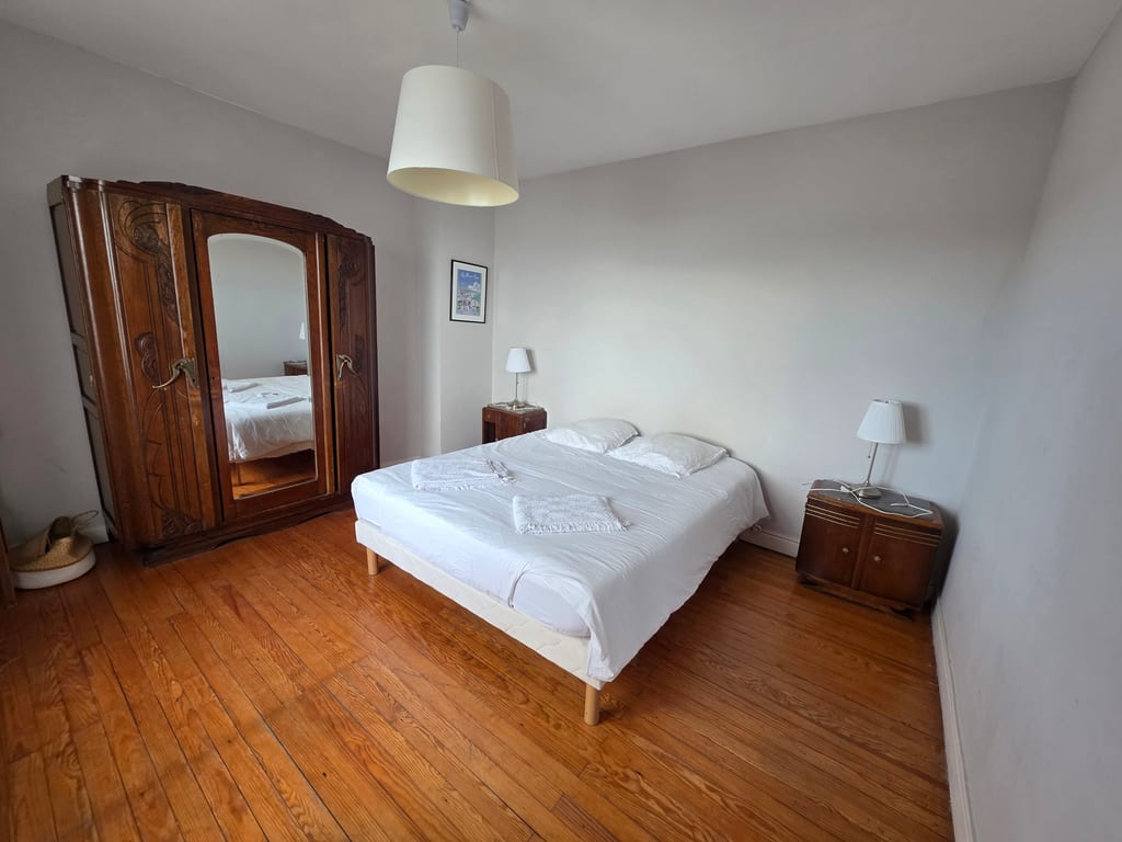 Chambre spacieuse avec parquet, lit double préparé et grande armoire en bois ancien. Une pièce lumineuse pour votre location vacances Côte d'Opale face à la mer.