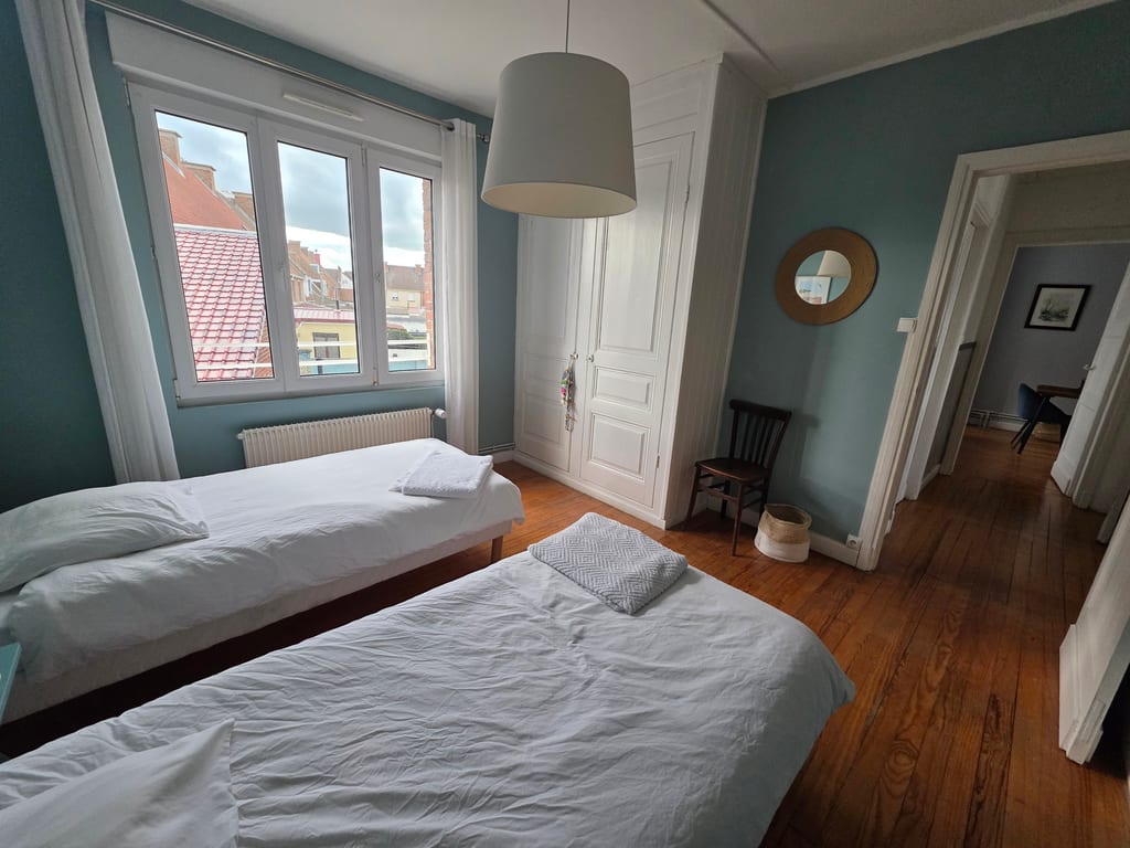 Seconde chambre aux teintes bleues marines avec deux lits simples et parquet, parfaite pour une location vacances Côte d'Opale en famille.