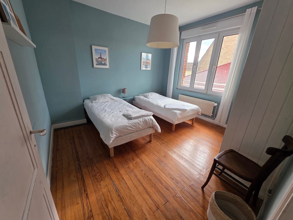 Chambre lumineuse avec deux lits simples et parquet en bois, idéale pour des vacances en famille sur le littoral Nord au Gîte Bouteille à la Mer.