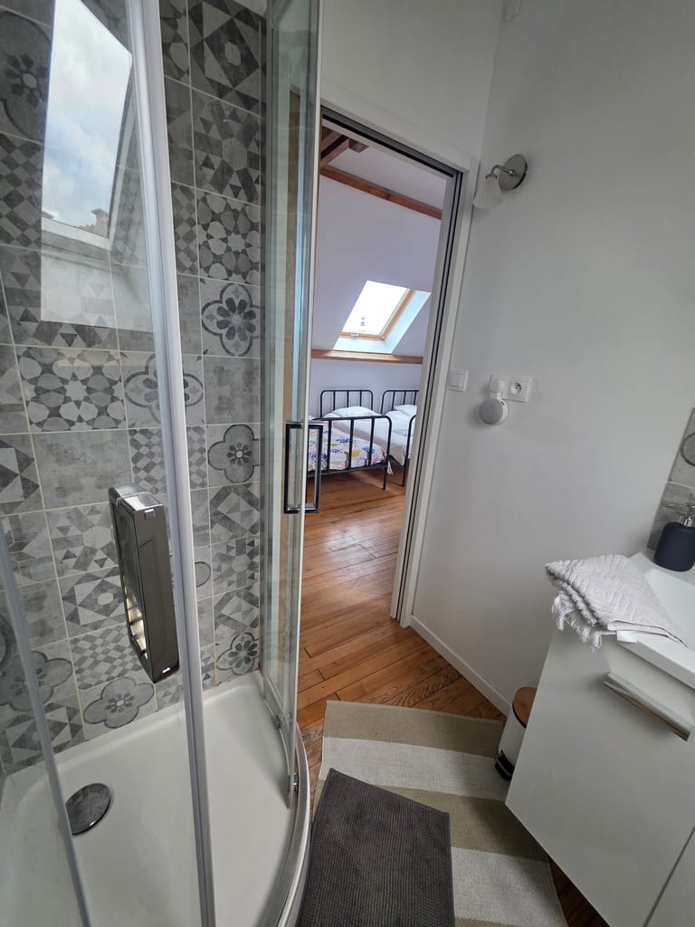 Salle de douche lumineuse et moderne ouverte sur un dortoir mansardé. L'aménagement idéal pour des vacances famille littoral Nord.