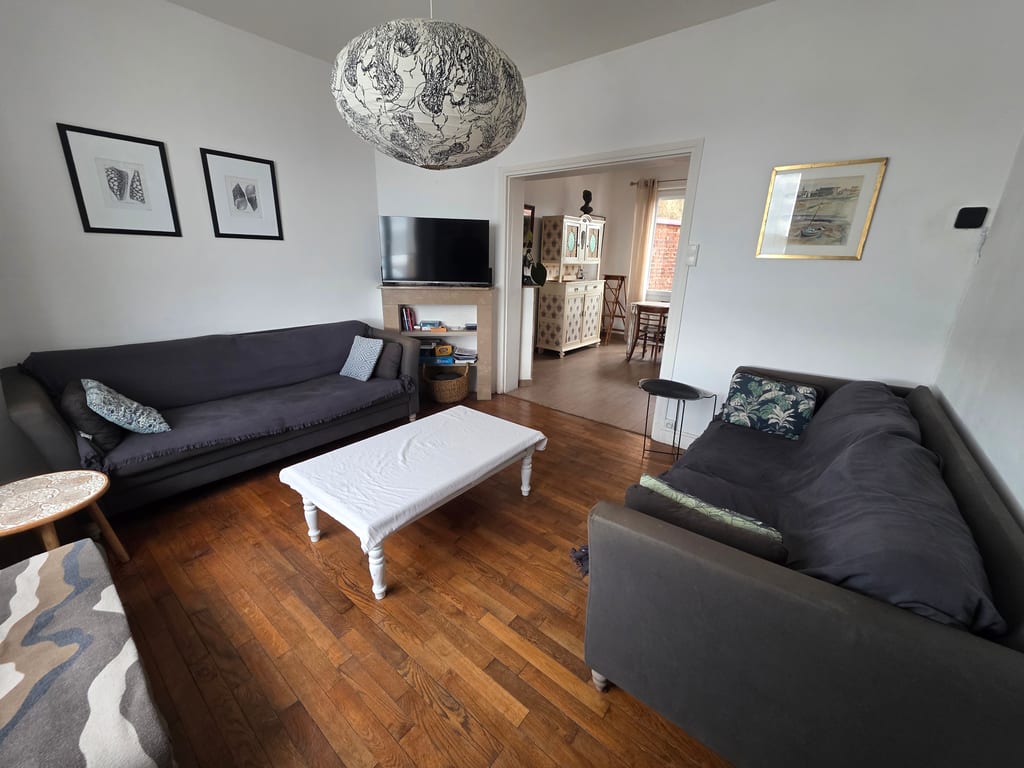Vaste salon au parquet de bois avec deux grands canapés confortables et une décoration soignée. Un espace détente parfait pour vos vacances en famille sur le littoral Nord.