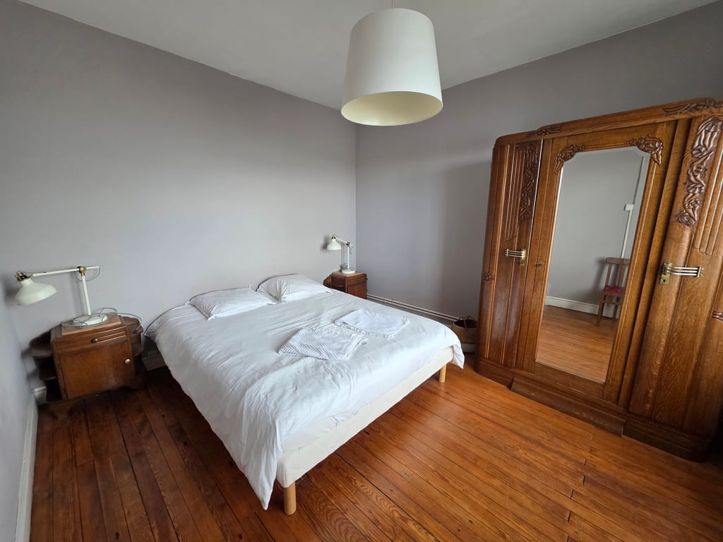 Grande chambre double dotée d'un parquet ancien, d'un grand lit et d'une armoire en bois sculpté, idéale pour un hébergement Dunkerque bord de mer.