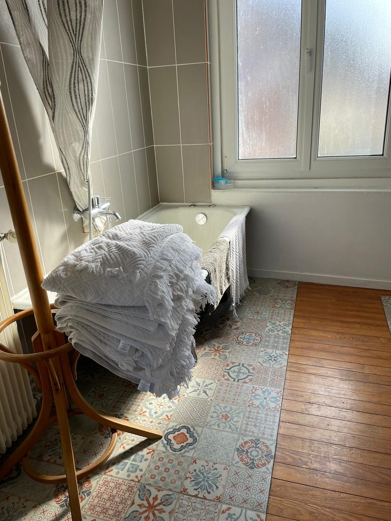 Pile de serviettes de bain propres sur un porte-manteau en bois dans une salle de bain rétro avec baignoire. Tout le confort attendu d'un hébergement Dunkerque bord de mer.