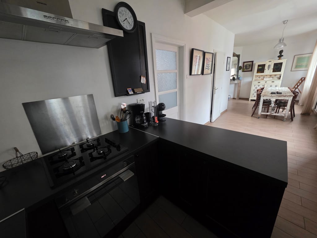 Vue depuis l'espace cuisine équipée vers la salle à manger conviviale du Gîte Bouteille à la Mer, un gîte 4 étoiles en Flandre maritime décoré dans un style marin authentique.