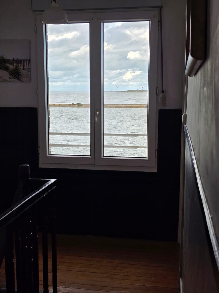 Vue dégagée sur le chenal et la mer depuis la fenêtre du palier au parquet en bois, atout charme de cette location saisonnière Grand-Fort-Philippe.